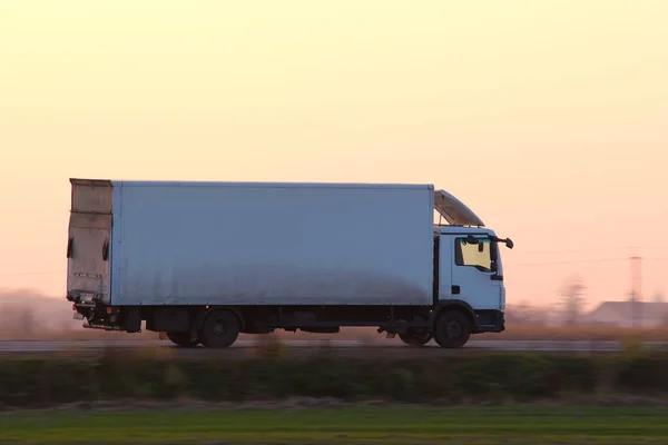 Camión de carga conduciendo en la carretera transportando mercancías por la noche. Transporte de entrega y concepto logístico — Foto de Stock