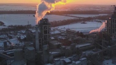 Gün batımında endüstriyel üretim alanında yüksek beton yapılı çimento fabrikası kulesinin havadan görüntüsü. Üretim ve küresel sanayi kavramı