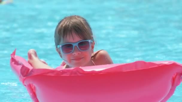 Niña feliz relajándose en colchón inflable del aire en piscina en día soleado del verano durante vacaciones tropicales. Concepto de actividades de verano — Vídeo de stock