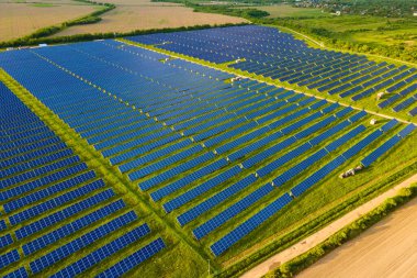 Temiz ekolojik elektrik enerjisi üretmek için birçok sıra güneş fotovoltaik paneli bulunan sürdürülebilir büyük elektrik santralinin havadan görünüşü. Sıfır emisyon kavramı ile yenilenebilir elektrik
