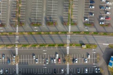 Otoparkta park yerleri ve yönler için çizgiler ve işaretlerle park edilmiş birçok renkli arabanın hava manzarası.