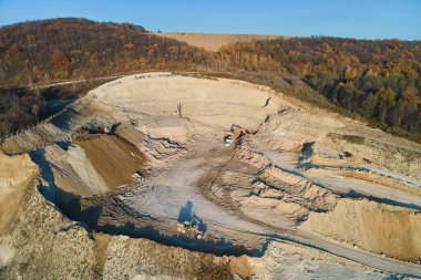 Kazı araçları ve çöp kamyonlarıyla inşaat endüstrisi için kireçtaşı malzemelerinin açık maden sahasının hava görüntüsü