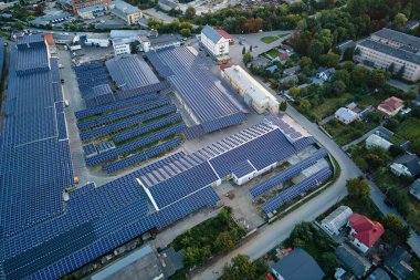 Sanayi binasının çatısına yeşil ekolojik elektrik üretmek için monte edilmiş mavi fotovoltaik panelli güneş enerjisi santralinin hava görüntüsü. Sürdürülebilir enerji konsepti üretimi