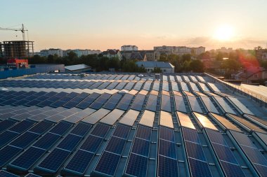 Mavi fotovoltaik güneş panelleri gün batımında temiz ekolojik elektrik üretmek için çatıya monte edildi. Yenilenebilir enerji konsepti üretimi