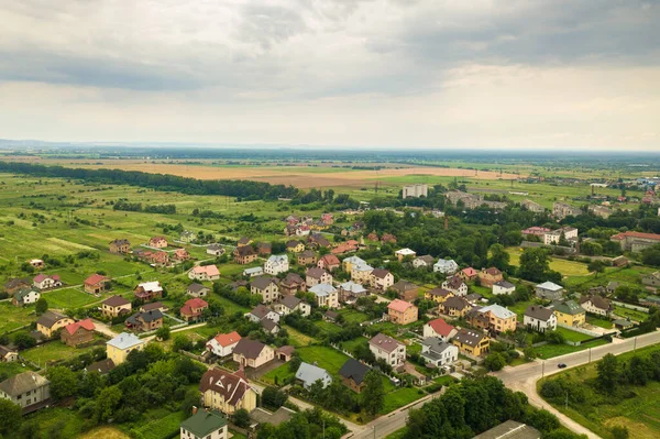 Vista aérea del paisaje de las casas de la aldea y los campos agrícolas cultivados verdes distantes con cultivos en el día brillante del verano — Foto de Stock