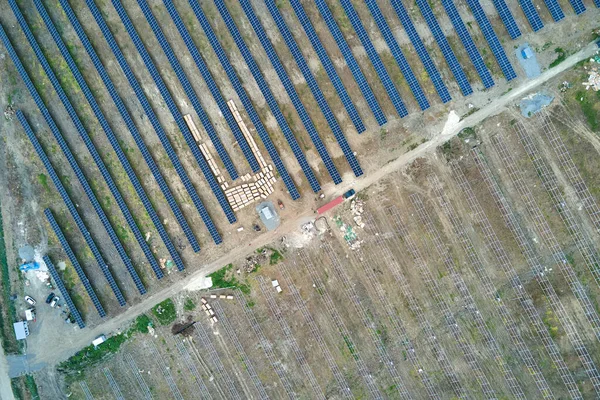 Widok z lotu ptaka na elektrownię w budowie z ciężarówką dostarczającą części montażowe do paneli słonecznych na metalowej ramie do produkcji energii elektrycznej. Rozwój energii elektrycznej ze źródeł odnawialnych — Zdjęcie stockowe
