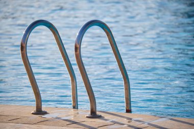 Yüzme havuzuna yakın paslanmaz çelik korkuluklar kaplumbağaların temiz havuz suyuna iniyor. Eğlence etkinlikleri kavramının erişilebilirliği