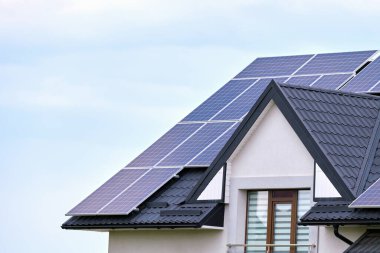 Banliyö bölgesinde temiz ekolojik elektrik enerjisi üretmek için güneş fotovoltaik panellerle kaplı çatısı olan bir ev. Özerk konut kavramı