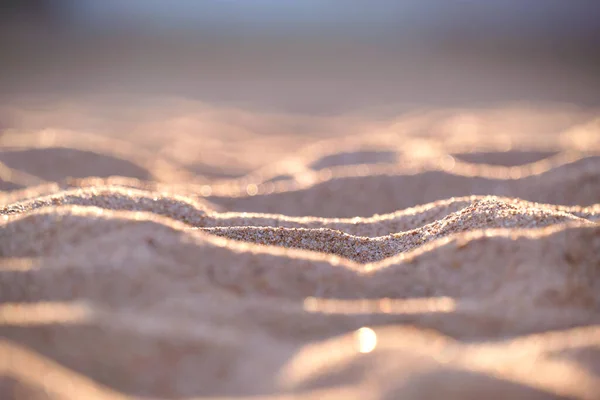 Close-up van schoon geel zandoppervlak dat zeestrand bedekt verlicht met avondlicht. Reis- en vakantieconcept — Stockfoto