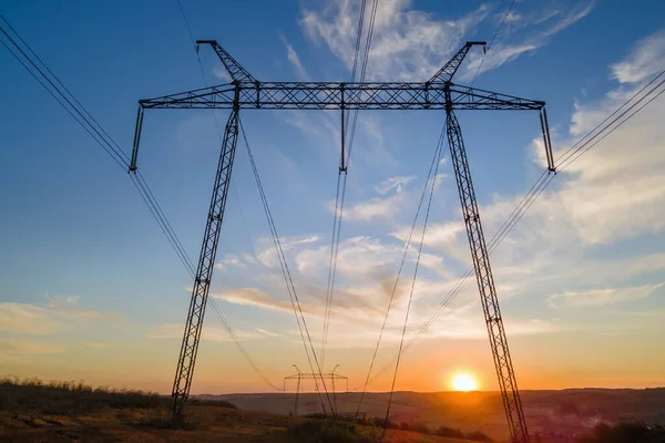 Torre de alta tensão com linhas eléctricas ao pôr-do-sol. Transmissão de electricidade — Fotografia de Stock
