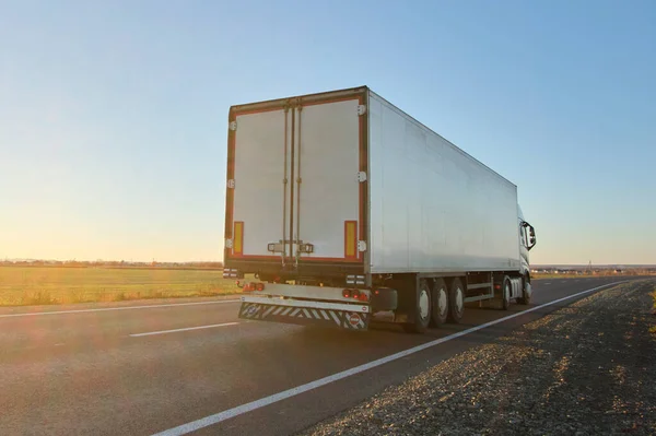 Semi-vrachtwagen met lading aanhangwagen rijden op de snelweg vervoeren goederen in de avond. Levering transport en logistiek concept — Stockfoto