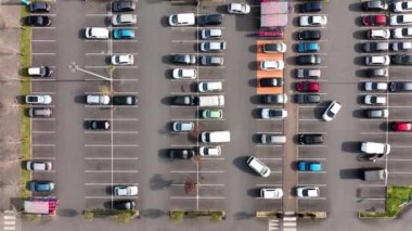 Otoparkta park yerleri ve yönler için çizgiler ve işaretlerle park edilmiş birçok renkli arabanın hava manzarası.