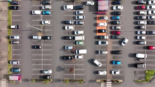Widok z lotu ptaka na wiele kolorowych samochodów zaparkowanych na parkingu z liniami i oznaczeniami miejsc parkingowych i kierunków — Wideo stockowe
