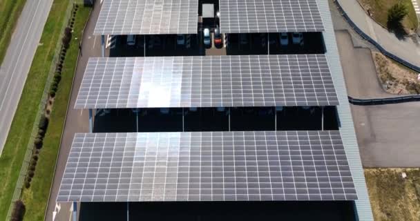 Luchtfoto van zonnepanelen geïnstalleerd als schaduwdak boven parkeerplaats met geparkeerde auto 's voor effectieve opwekking van schone elektriciteit. Fotovoltaïsche technologie geïntegreerd in stedelijke infrastructuur — Stockvideo