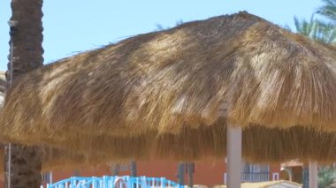 Tropik tatil beldesindeki deniz kenarındaki saman gölgesi şemsiyelerinin ayrıntıları. Yaz tatilleri ve kaçış konsepti