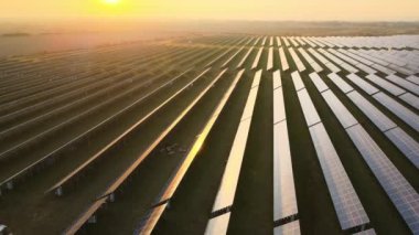Akşamları temiz elektrik enerjisi üretmek için sıra sıra güneş fotovoltaik panelleri olan sürdürülebilir büyük elektrik santralinin havadan görünüşü. Sıfır emisyonlu yenilenebilir elektrik kavramı