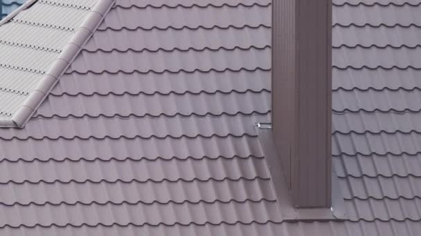 Chimenea en la azotea de la casa cubierta con tejas metálicas en construcción. Revestimiento de azulejos del edificio. Desarrollo inmobiliario — Vídeos de Stock