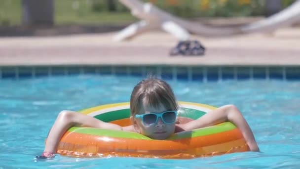 Portret van een gelukkig kind meisje ontspannen in opblaasbare cirkel in het zwembad op zonnige zomerdag tijdens tropische vakanties. Begrip activiteiten in de zomer — Stockvideo