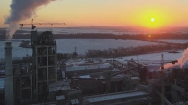 Gün batımında endüstriyel üretim alanında yüksek beton yapılı çimento fabrikası kulesinin havadan görüntüsü. Üretim ve küresel sanayi kavramı