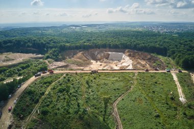 Kazı araçları ve çöp kamyonları ile inşaat endüstrisi için kireçtaşı malzemelerinin açık çukur madenciliğinin hava görüntüsü