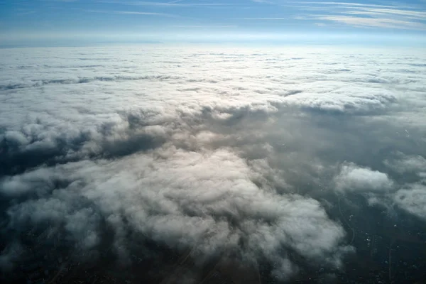 Aerial view from high altitude of distant city covered with puffy cumulus clouds forming before rainstorm. Airplane point of view of cloudy landscape — Stock Photo, Image