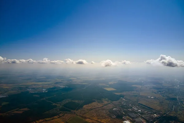Воздушный вид с большой высоты далекого города, покрытый пышными кучевыми облаками, образующимися перед ливнем. Авиационная точка зрения облачного ландшафта — стоковое фото