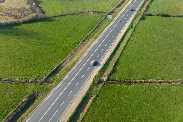 Luchtfoto van de intercity weg tussen groene landbouwvelden met snelrijdende auto 's. Top uitzicht van drone van het verkeer op de snelweg — Stockfoto