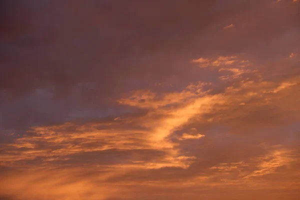 Bright colorful sunset sky with vivid smooth clouds illuminated with setting sun light spreading to horizon — Fotografia de Stock