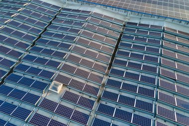 Sanayi binasının çatısına yeşil ekolojik elektrik üretmek için monte edilen mavi fotovoltaik güneş panellerinin hava görüntüsü. Sürdürülebilir enerji konsepti üretimi