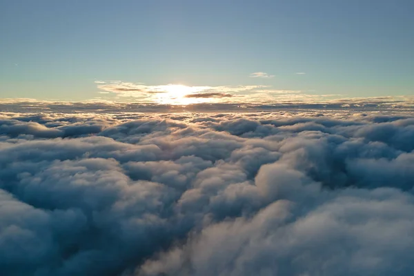 Aerial view from above at high altitude of dense puffy cumulus clouds flying in evening. Amazing sunset from airplane window point of view — Stock Photo, Image