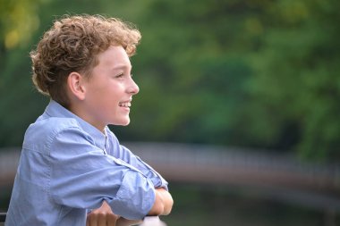 Genç mutlu çocuk yaz parkında dinleniyor. Yazın dışarıda eğlenen pozitif çocuk. Çocuk esenliği kavramı