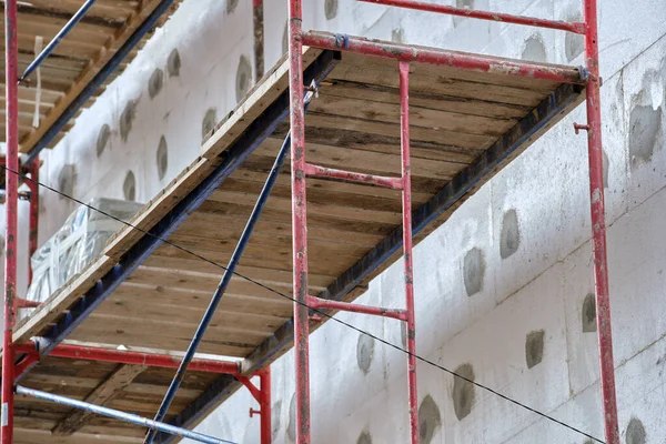 Fachada del edificio en obras de renovación con marco de andamio de construcción. Aislamiento de pared con láminas de espuma de poliestireno para un hogar eficiente — Foto de Stock