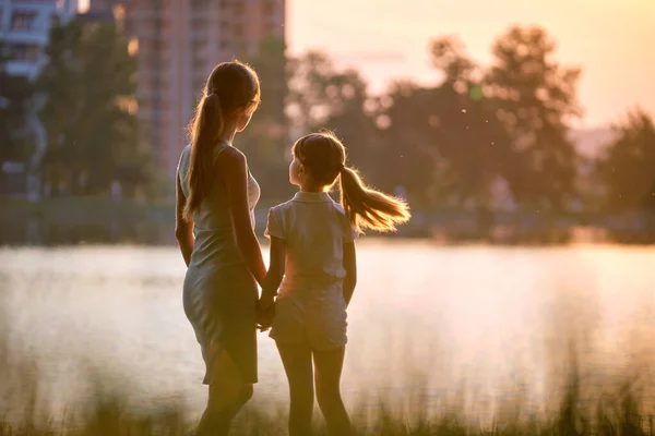 해 가 지는 여름 공원에서 손을 잡고 즐거운 시간을 보내는 행복 한 어머니와 딸. 가족 의사 랑 과 관계 개념 — 스톡 사진
