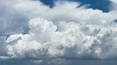 Beyaz kabarık kümülüs bulutlarının zamanı yaz mavi gökyüzünde şekilleniyor. Hareket eden ve değişen bulutlu hava durumu
