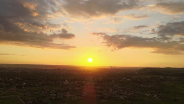 Vista aérea da paisagem de casas de aldeia e campos agrícolas cultivados verdes distantes com culturas crescentes na noite de verão brilhante — Vídeo de Stock