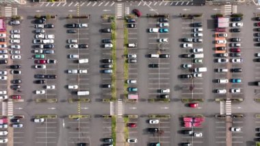 Otoparkta park yerleri ve yönler için çizgiler ve işaretlerle park edilmiş birçok renkli arabanın hava manzarası.