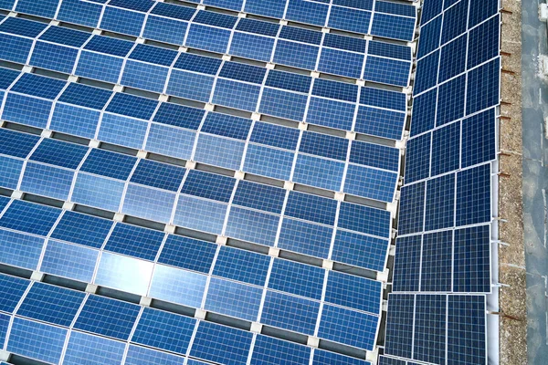 Вид с воздуха на голубые фотоэлектрические солнечные панели, установленные на крыше промышленного здания для производства зеленой экологической электроэнергии. Производство концепции устойчивой энергетики — стоковое фото