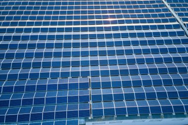 Sanayi binasının çatısına yeşil ekolojik elektrik üretmek için monte edilmiş mavi fotovoltaik panelli güneş enerjisi santralinin hava görüntüsü. Sürdürülebilir enerji konsepti üretimi