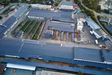 Sanayi binasının çatısına yeşil ekolojik elektrik üretmek için monte edilmiş mavi fotovoltaik panelli güneş enerjisi santralinin hava görüntüsü. Sürdürülebilir enerji konsepti üretimi
