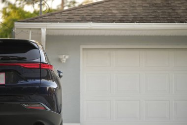 Car parked in front of wide garage double door on concrete driveway of new modern american house