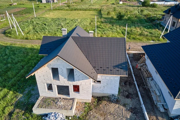 建設中の金属タイルで覆われた軽量コンクリート壁や木製の屋根フレームと未完成の家の空中ビュー — ストック写真
