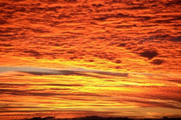 Яркое красочное небо заката с яркими гладкими облаками, освещенными закатом солнечного света, распространяющегося на горизонт — стоковое фото
