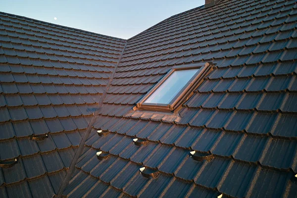 Nahaufnahme eines Dachbodenfensters auf dem Hausdach, das mit Keramikschindeln abgedeckt ist. Fliesenverkleidung des Gebäudes — Stockfoto