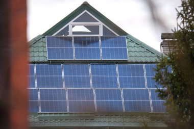 Banliyö bölgesinde temiz ekolojik elektrik enerjisi üretmek için güneş fotovoltaik panellerle kaplı çatısı olan bir ev. Özerk konut kavramı