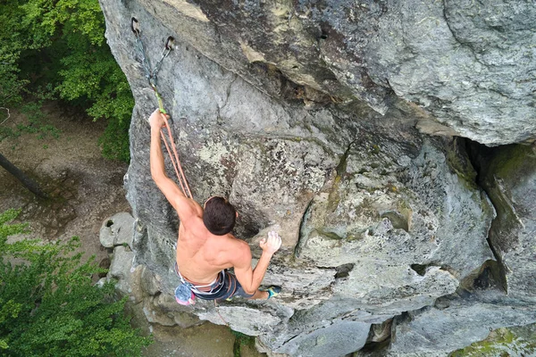 Mladý muž šplhá po strmé stěně skalnaté hory. Muž horolezec překonává náročnou trasu. Zapojení do konceptu extrémního sportu — Stock fotografie