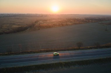 Bulanık hızlı sürüş yapan şehirlerarası yolun hava manzarası gün batımında çevre dostu elektrikli araba. Akşamları otoban trafiğinin insansız hava aracı görüntüsü