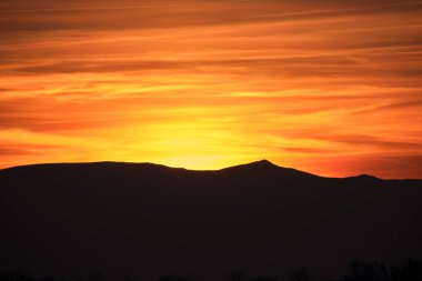 Güzel bir akşam panoramik manzarası. Gün batımında uzak dağ tepeleri üzerinde parlak batan güneş.