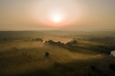 Parlak renkli günbatımı gökyüzü, batan güneş ve canlı bulutlar, karanlık manzaranın üzerinde.