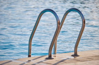 Yüzme havuzuna yakın paslanmaz çelik korkuluklar kaplumbağaların temiz havuz suyuna iniyor. Eğlence etkinlikleri kavramının erişilebilirliği