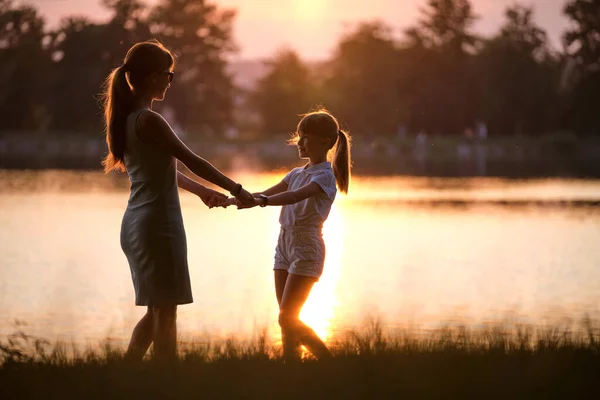 Mutlu anne ve kız el ele tutuşup gün batımında yaz parkında eğleniyorlar. Aile sevgisi ve ilişki kavramı — Stok fotoğraf